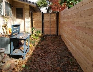 A house and sideyard with horizontal cedar wood fence and gate with black steel frame